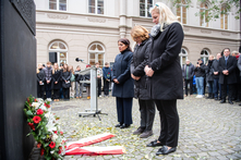 Die Präsidentin und die Vizepräsidentinnen stehen mit gesenkten Köpfen vor dem Mahnmal. Auf dem Boden liegt ein Kranz mit Schleife.